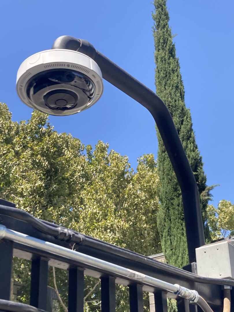 A street light with a camera hanging from it's side.